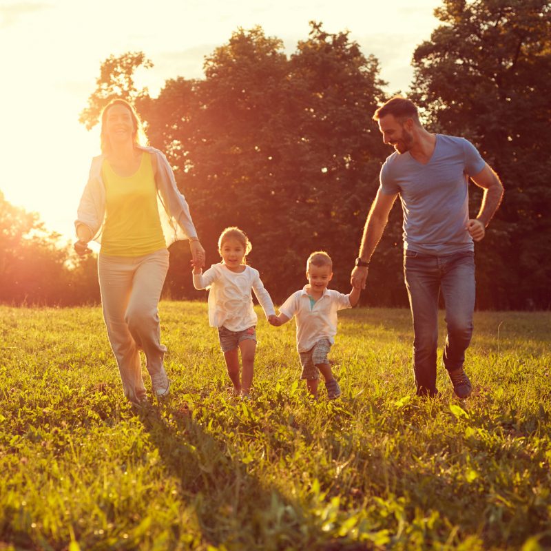 Happy young children with parents running in park